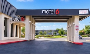 A motel with a covered parking area and a sign indicating a 11'-8' clearance. - Motel 6 Claremont, CA (Claremont)