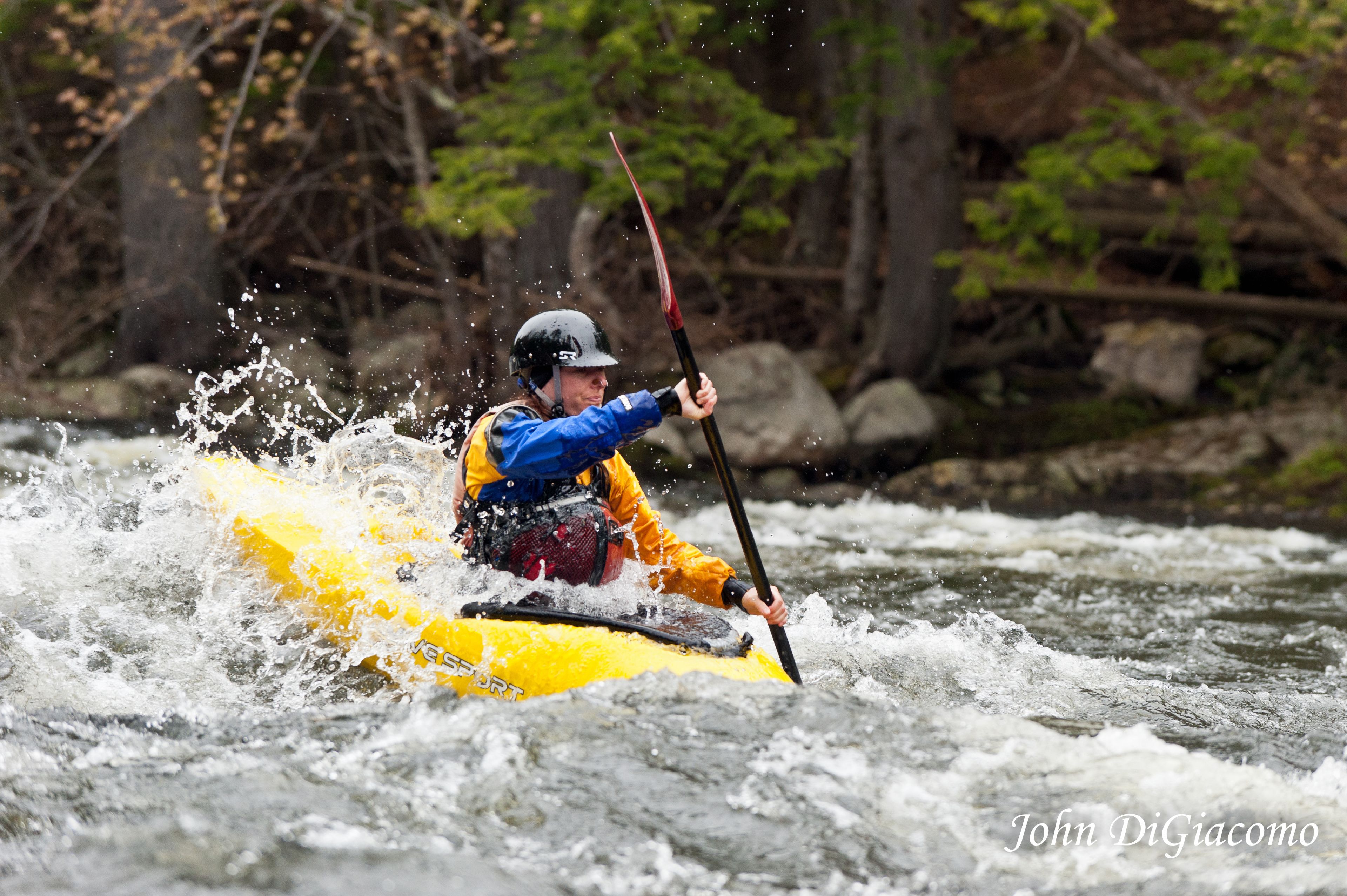 Eine Person paddelt auf einem Fluss mit einem Kajak.