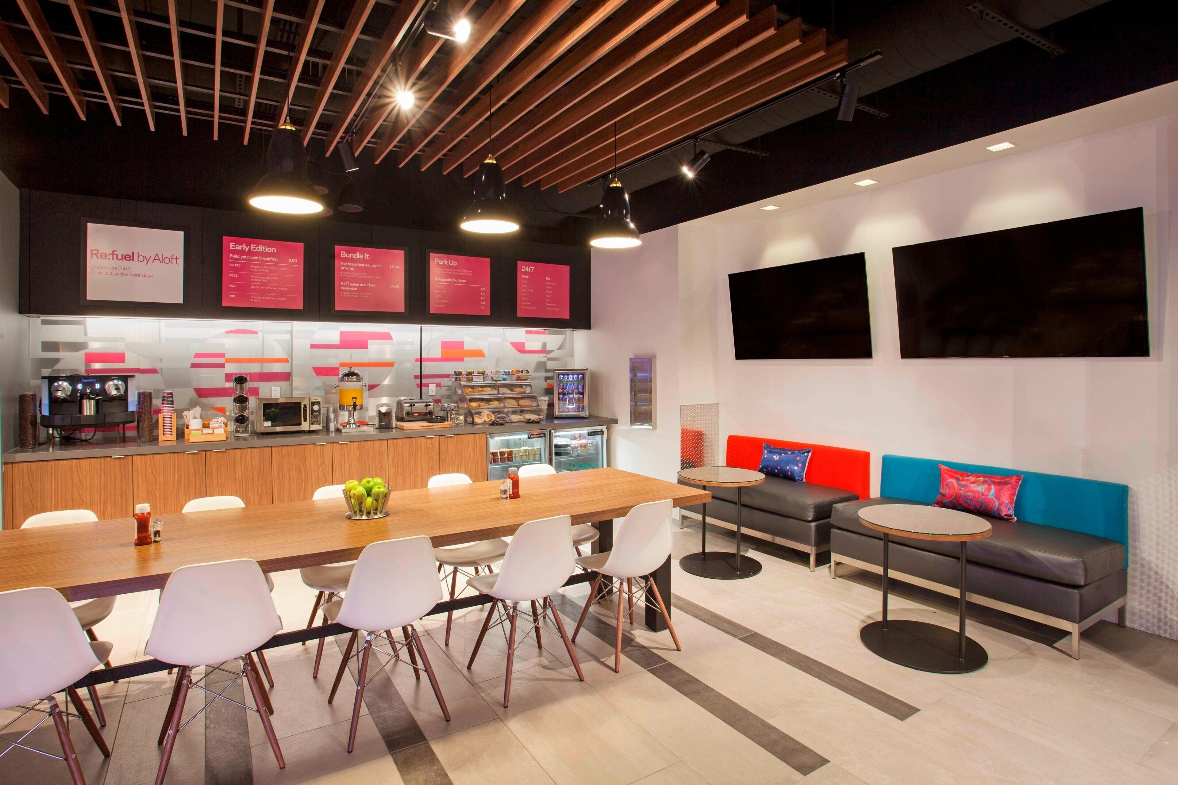 Un espace cuisine moderne doté d’un long comptoir, de chaises blanches et d’un coin salon avec des canapés et une table.