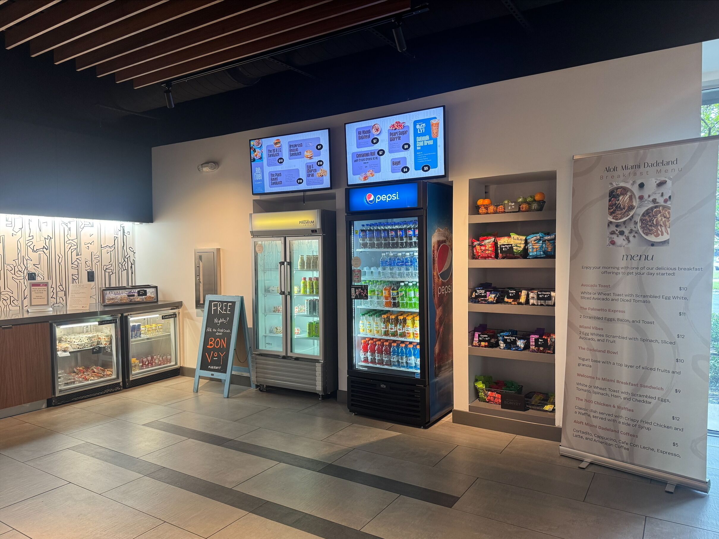 A breakfast area with a menu board, refrigerated display cases, and a Pepsi refrigerator.