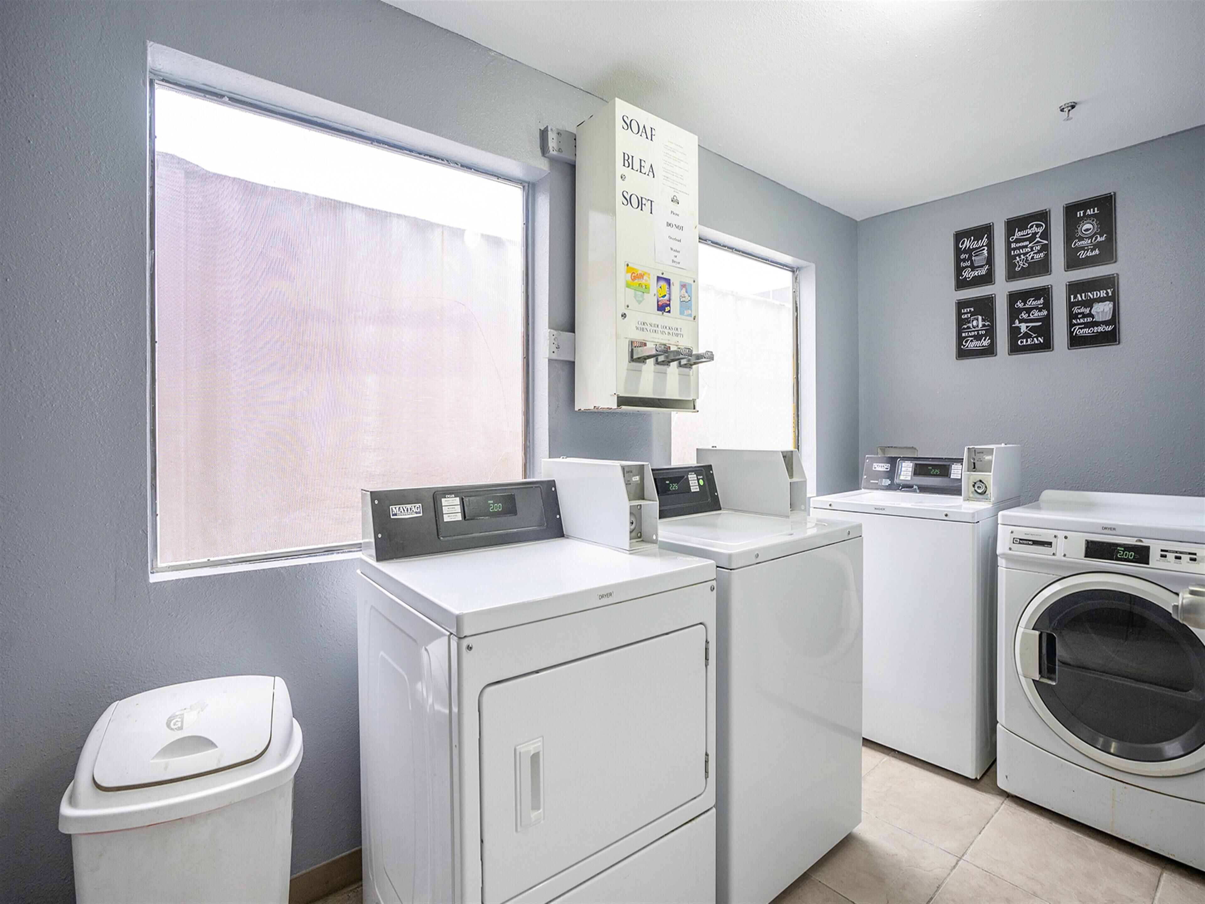 A laundry room with a washing machine, dryer, and a wall-mounted soap dispenser.