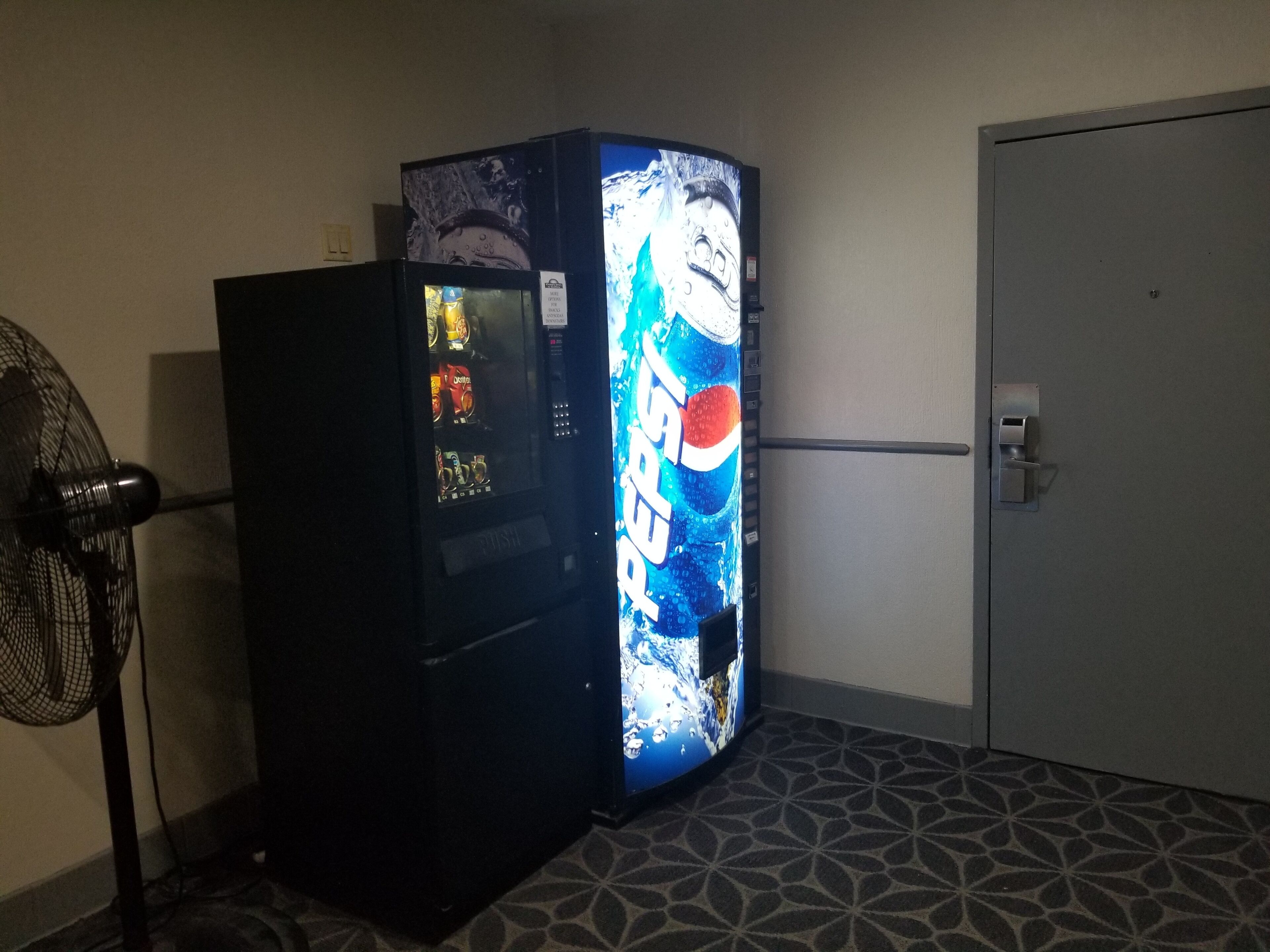 A vending machine with a Pepsi logo, a door, and a patterned floor.