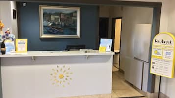 A reception desk with a framed painting above it, a sign for Daybreak Breakfast, and a sun design on the desk.