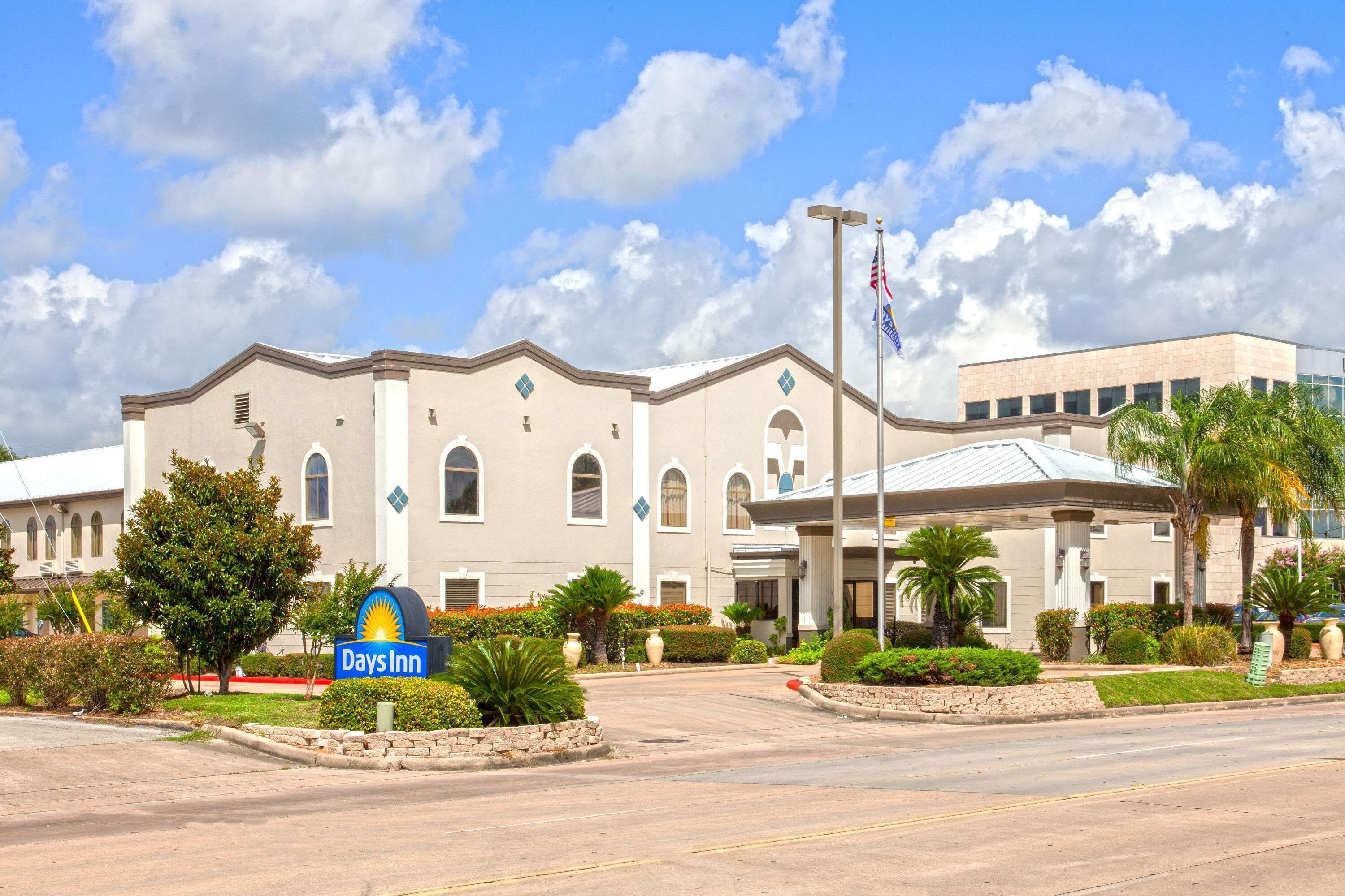 A Days Inn hotel with a large entrance, a flagpole with flags, and well-maintained landscaping.