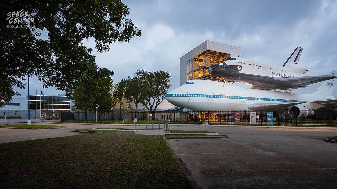 Une grande navette spatiale exposée dans un musée, avec un bâtiment en arrière-plan.