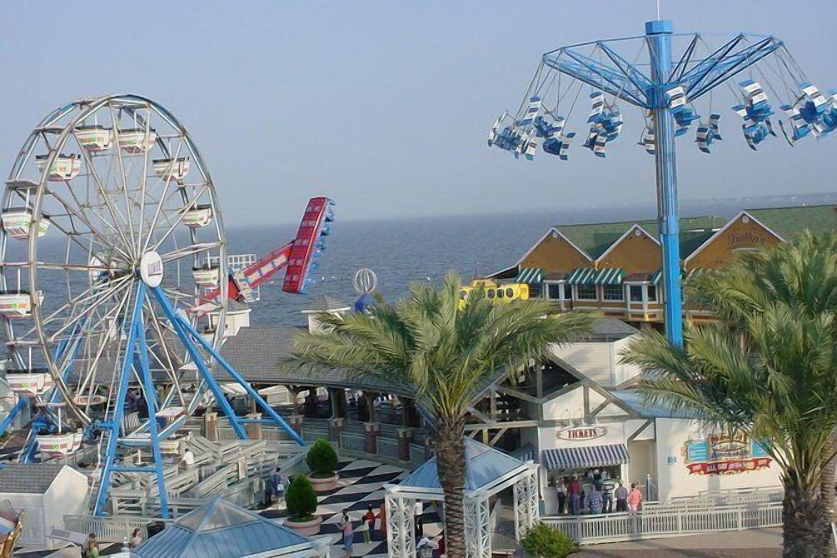 A Ferris wheel, a swing ride, and a building with a sign that reads "Tickets".