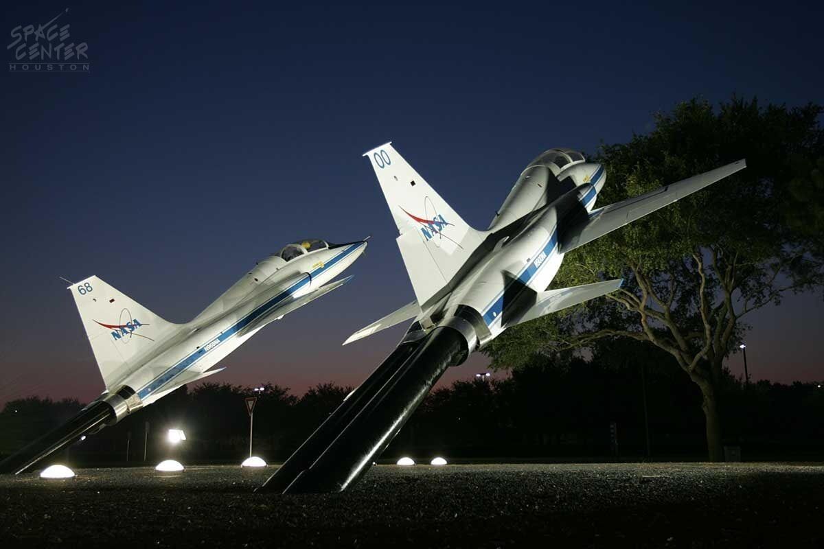 Two space shuttle models displayed outdoors at night.