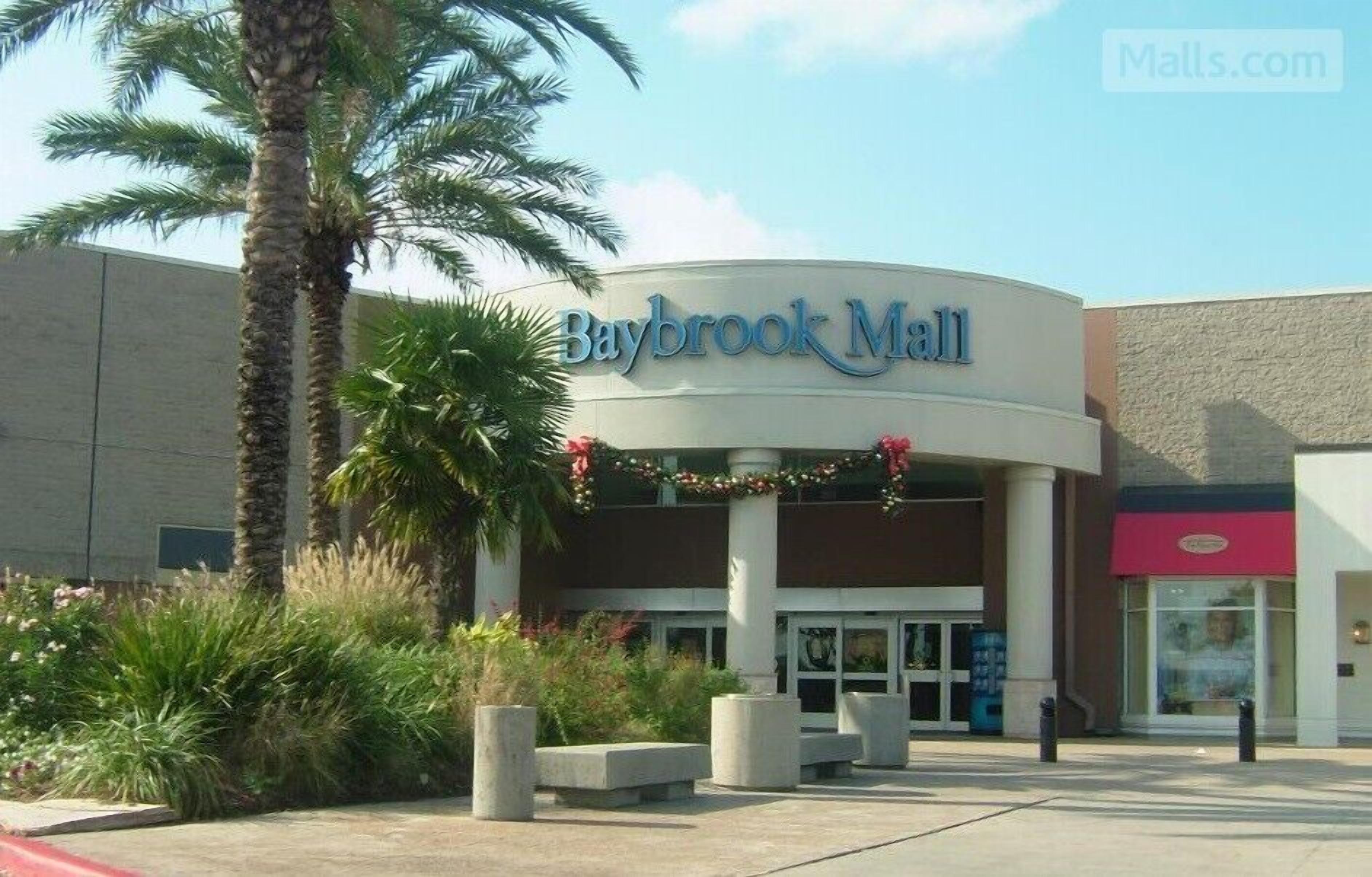 The exterior of Baybrook Mall with a curved entrance, palm trees, and a clear sky.