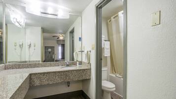 A bathroom with a granite countertop sink, a mirror, a ceiling fan, and a toilet.