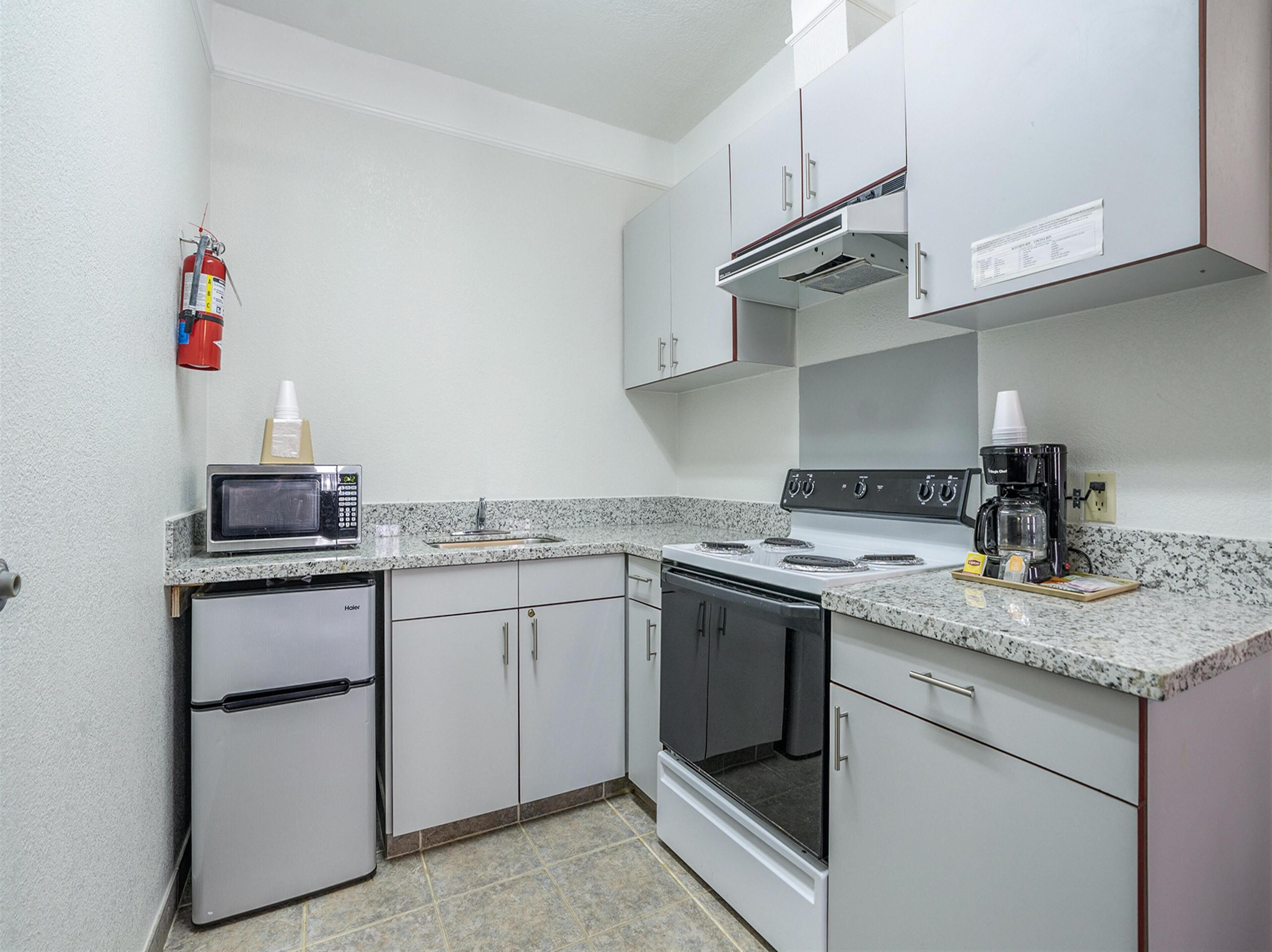 A compact kitchen with a refrigerator, stove, microwave, and coffee maker.