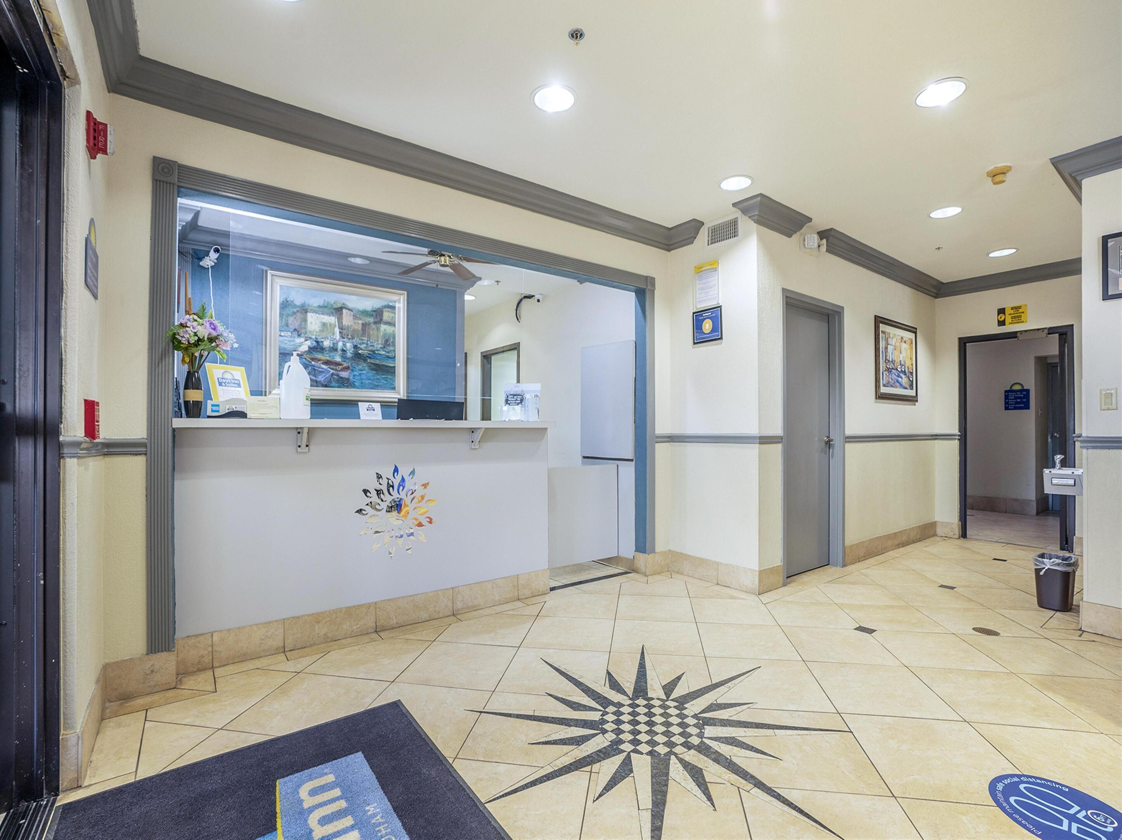 A reception area with a reception desk, a framed painting, a ceiling fan, and a tiled floor with a star pattern.