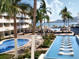 Un resort con piscina, palmeras y vista al mar.