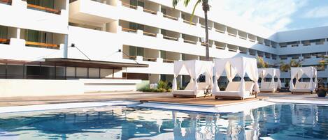 A modern hotel with a pool, multiple balconies, and outdoor seating areas.