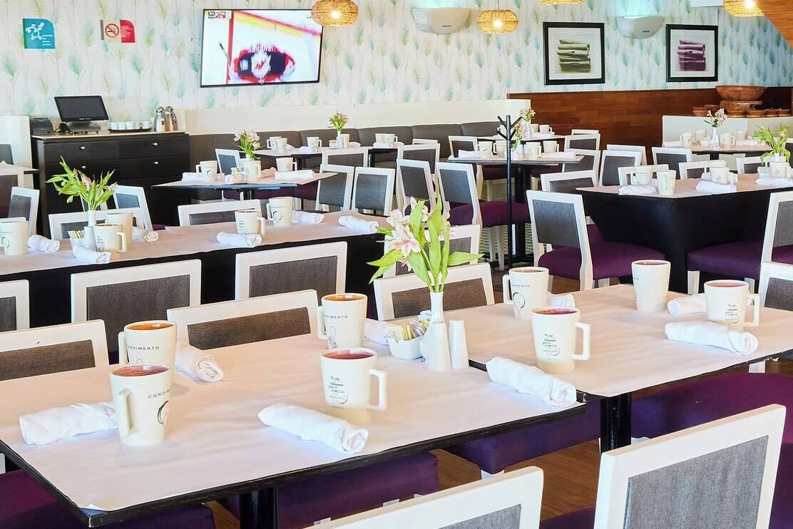 A restaurant with multiple tables, each set with white mugs and napkins.