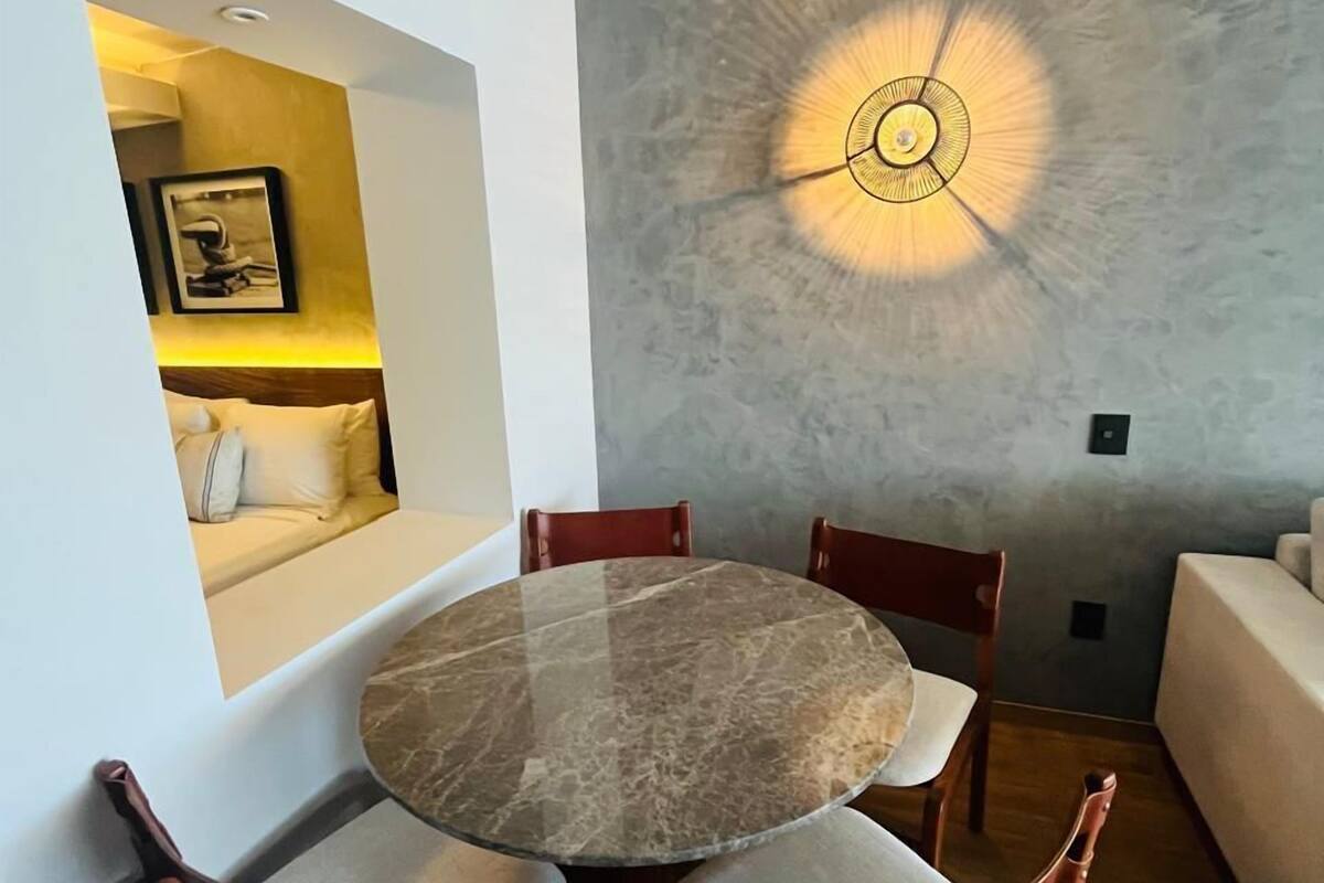 A dining area with a round marble table, wooden chairs, and a modern ceiling light fixture.