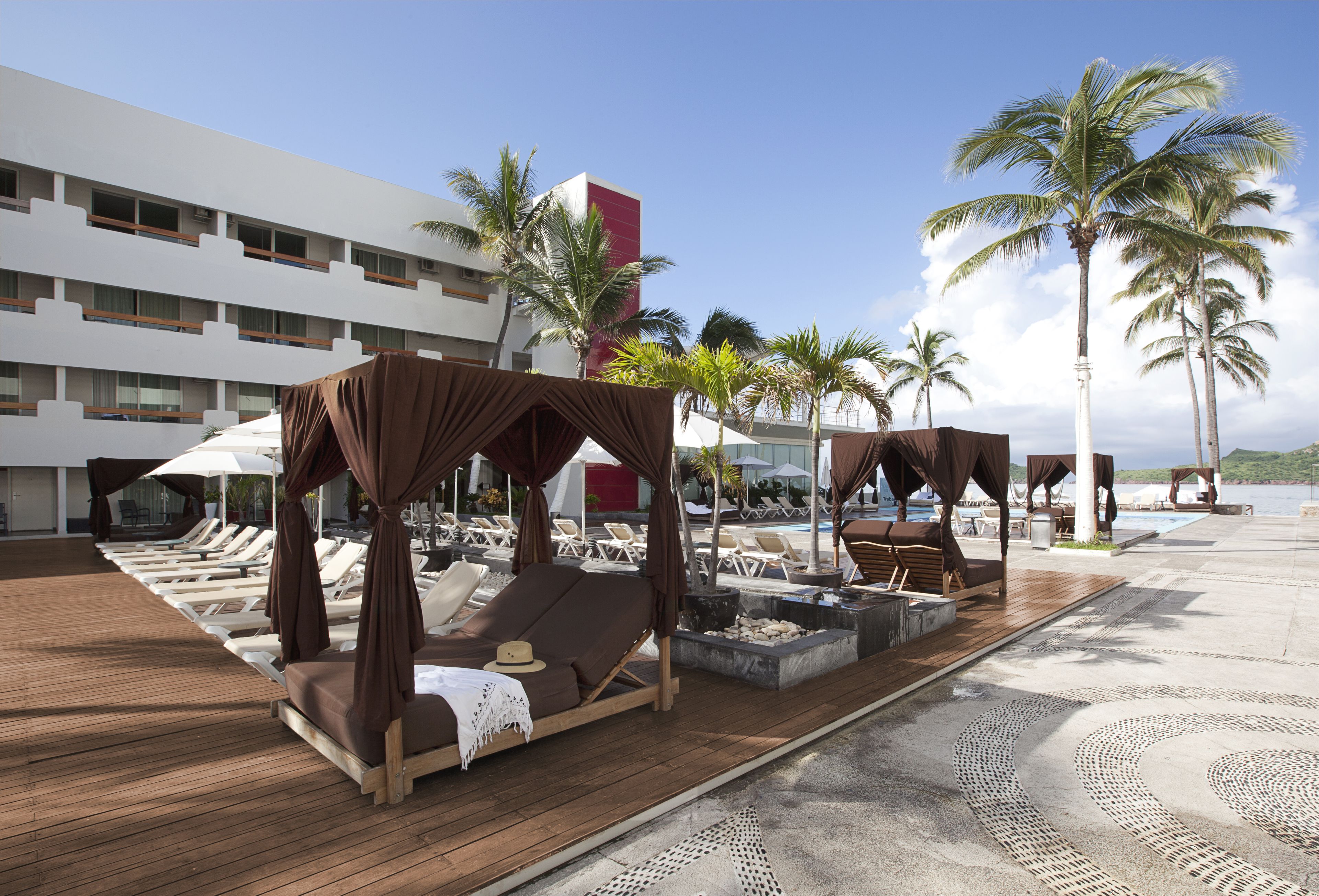Un resort con áreas de estar al aire libre, palmeras y una piscina.