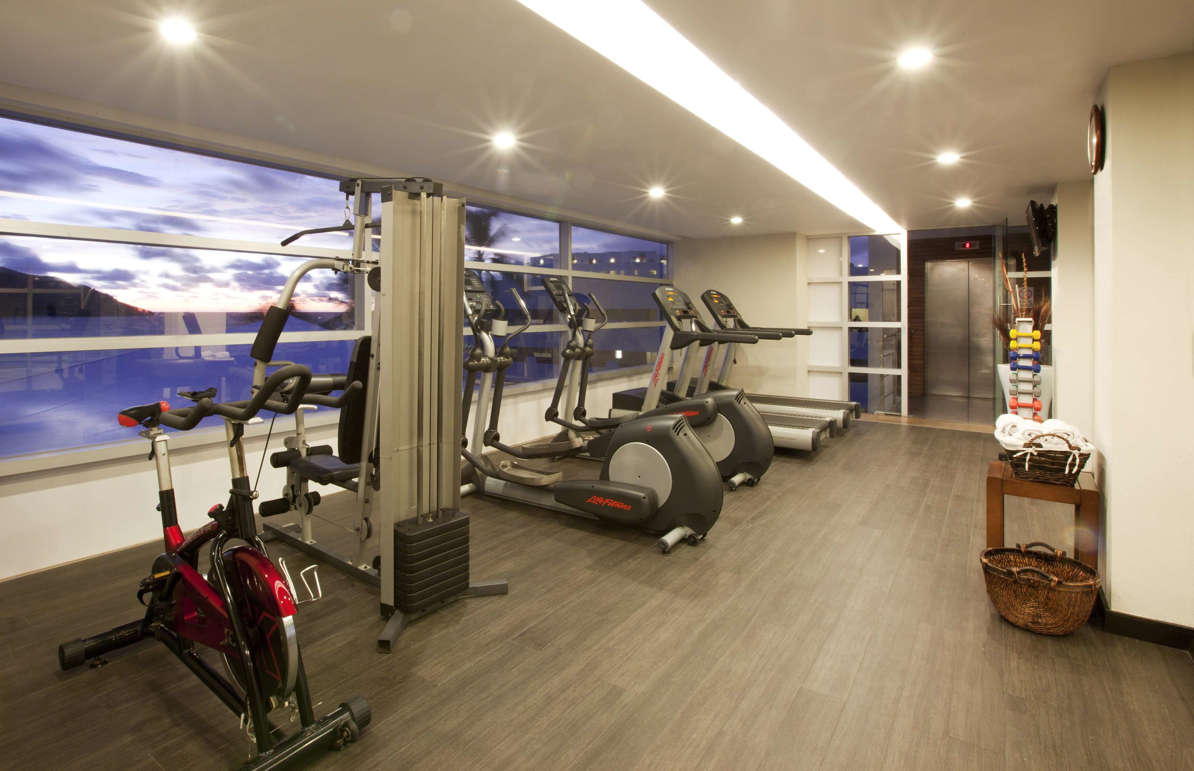 A gym with cardio machines, a weight bench, and a window with a view.