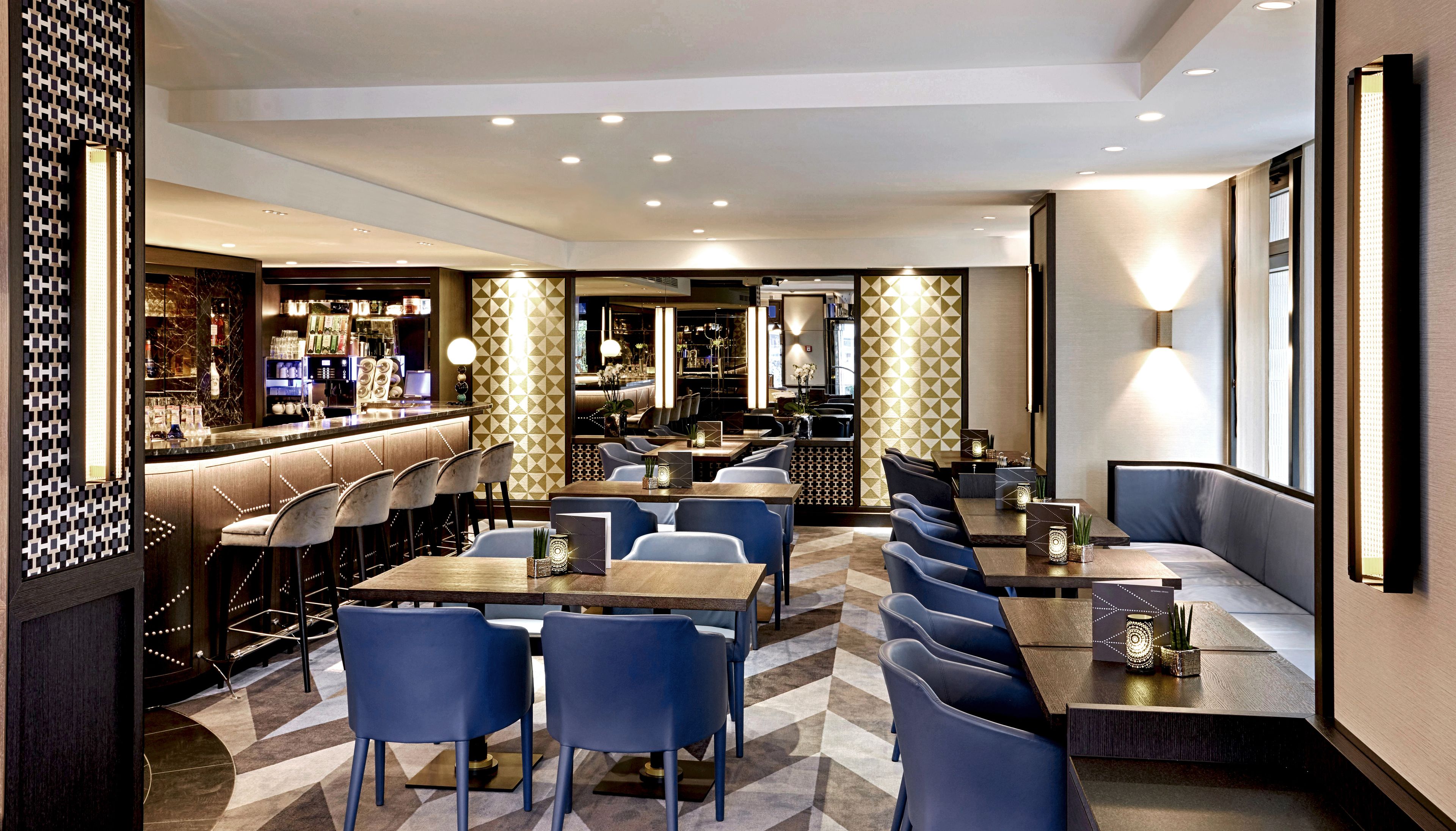 A modern restaurant with a bar area, multiple seating options including booths and tables, and a patterned floor.