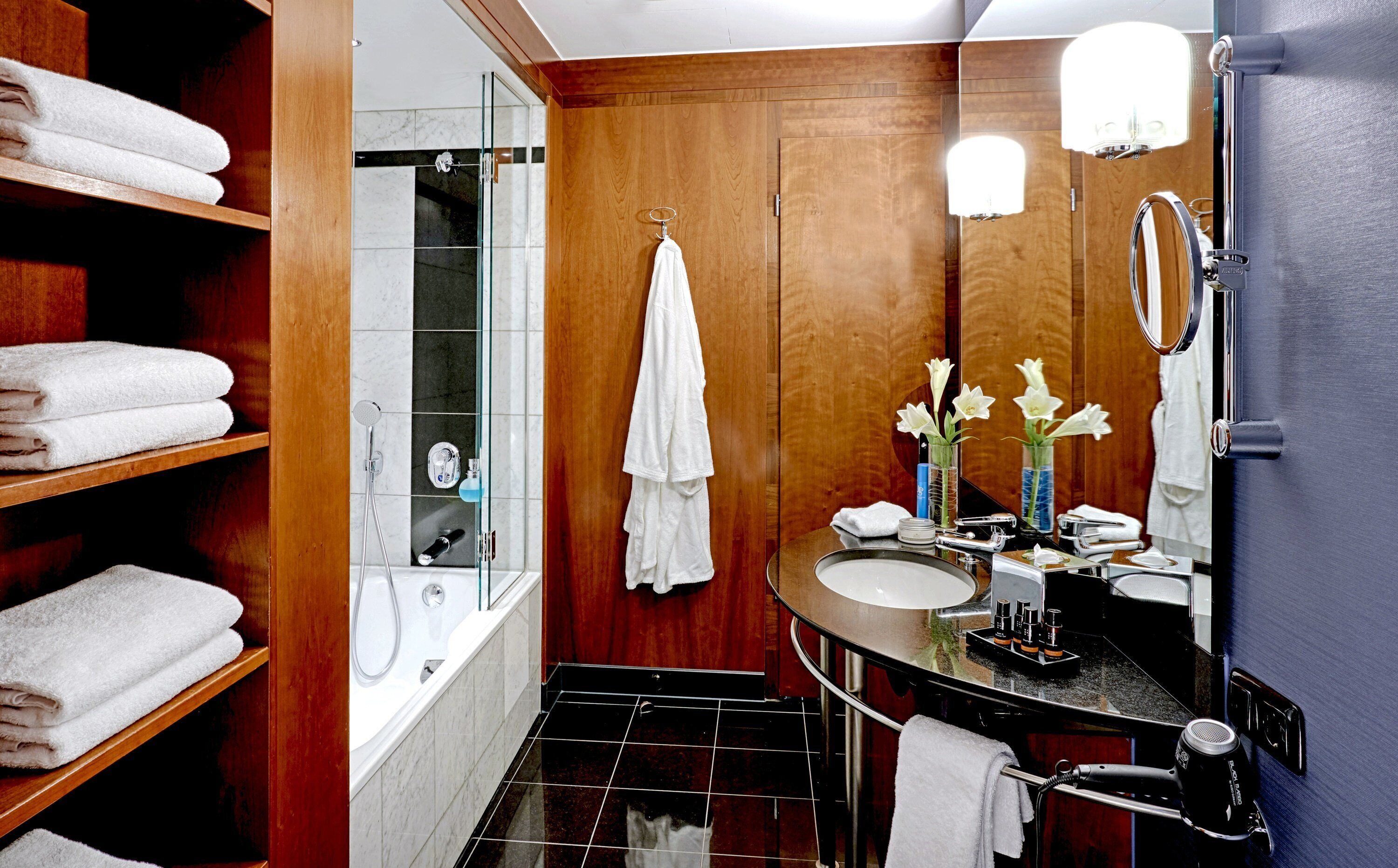 A modern bathroom with a glass-enclosed shower, wooden vanity, and a large mirror.