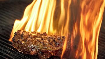 Ein Steak wird über offenem Feuer gegrillt.
