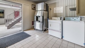 A laundry area with a Whirlpool washer and dryer, a stainless steel refrigerator, and a sign indicating guest laundry rules. - Red Roof Inn Lewisville (Lewisville)