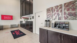 A modern hotel lobby with a reception desk, a coffee station, and artwork on the walls. - Red Roof Inn Lewisville (Lewisville)