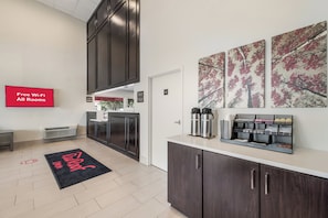 A modern hotel lobby with a reception desk, a coffee station, and artwork on the walls. - Red Roof Inn Lewisville (Lewisville)