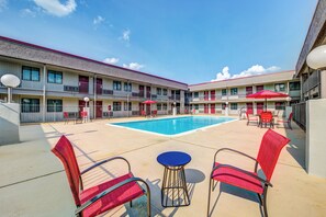 A hotel with a swimming pool, red chairs, and umbrellas. - Red Roof Inn Lewisville (Lewisville)