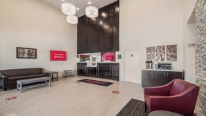 A modern lobby with a reception desk, seating area, and a check-in counter. - Red Roof Inn Lewisville (Lewisville)