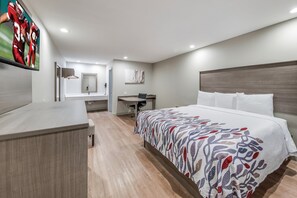 A modern hotel room with a large bed, a desk, and a TV mounted on the wall. - Red Roof Inn Lewisville (Lewisville)