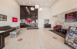 A hotel lobby with a reception desk, a sofa, a coffee table, and a Red Roof Inn sign.