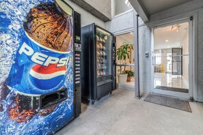 A vending machine with a Pepsi logo, a glass door entrance, and a potted plant inside. - Red Roof Inn Lewisville (Lewisville)
