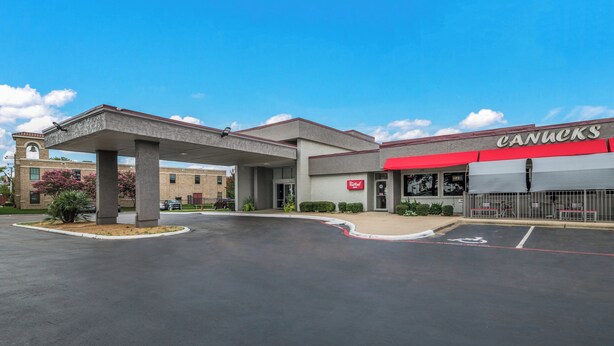 A gas station with a Canucks sign, a red awning, and a bell tower. - Red Roof Inn Lewisville (Lewisville)