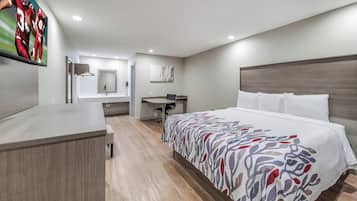 Ein Hotelzimmer mit Bett, Schreibtisch, Stuhl, Fernseher und Bad.