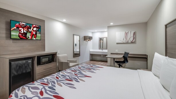 A hotel room with a bed, a desk, a chair, a television, and a bathroom. - Red Roof Inn Lewisville (Lewisville)