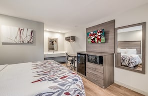 Une chambre d’hôtel moderne équipée d’un lit, d’un bureau, d’un miroir et d’une télévision.