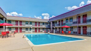A motel with a swimming pool, outdoor seating, and multiple balconies. - Red Roof Inn Lewisville (Lewisville)