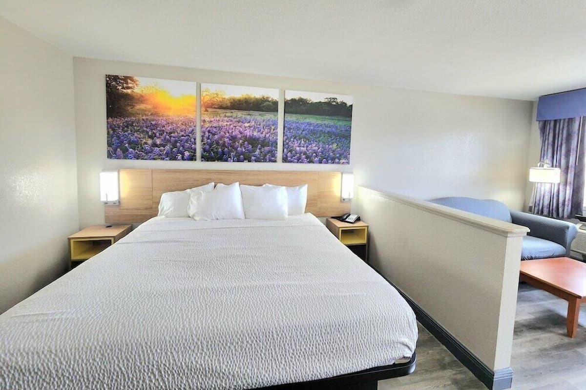 A hotel room with a large bed, a headboard, a nightstand, a desk, and a chair.