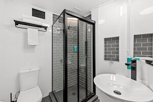 Un bagno moderno con doccia vetrata, lavandino bianco e vaso.
