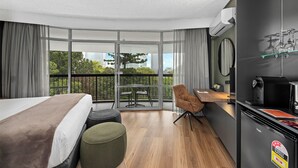 A modern hotel room with a large bed, a small table, a chair, a balcony with a view of the city, and a kitchenette. - Tower Mill Hotel (Spring Hill)