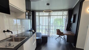 A modern kitchen with dark wood flooring, white cabinetry, and a dining area with a chair and table. - Tower Mill Hotel (Spring Hill)