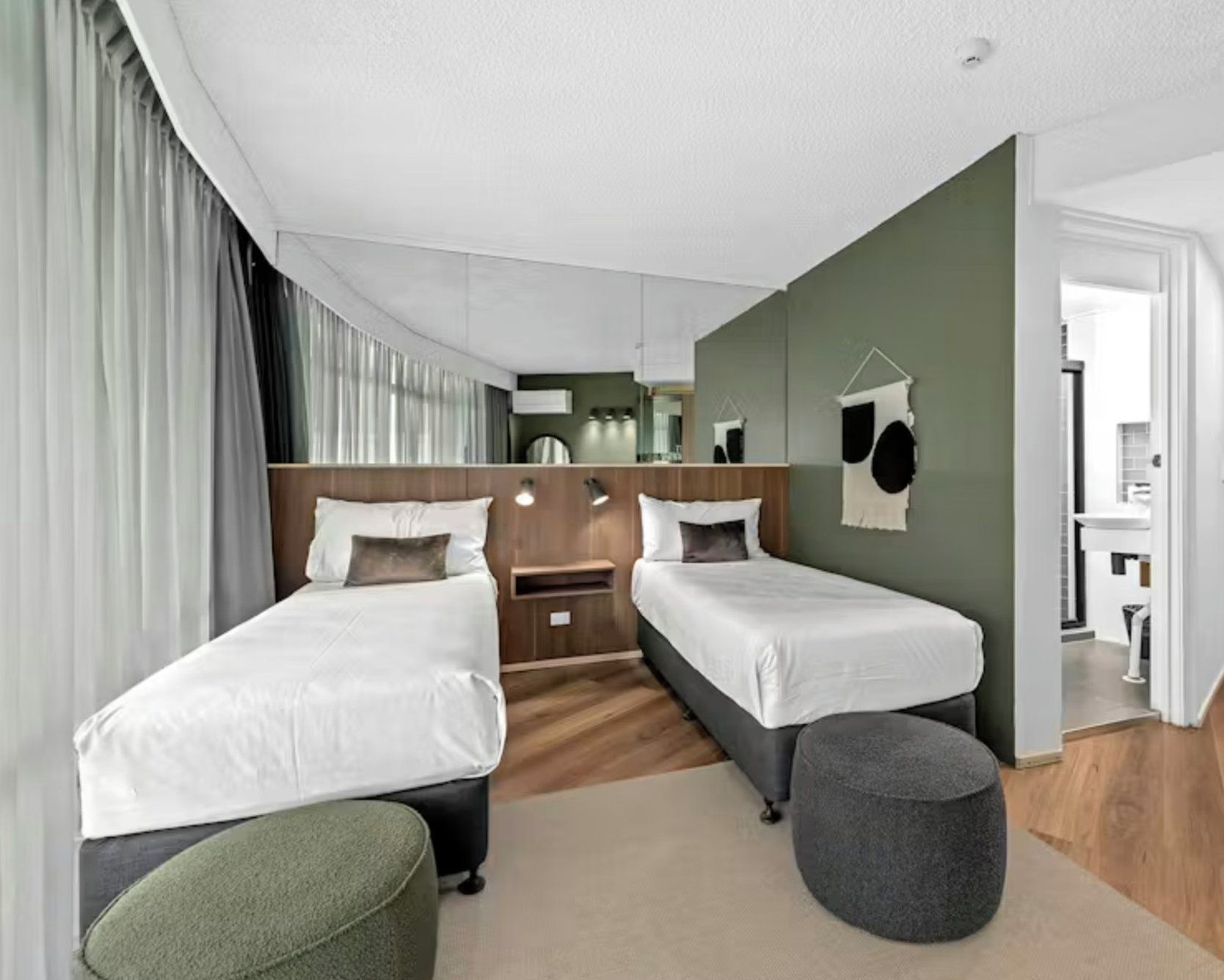 A hotel room with two beds, a small desk, a mirror, and a hanging light fixture.