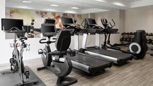 Une salle de sport moderne équipée de tapis de course, de vélos elliptiques et d’un appareil d’aviron.