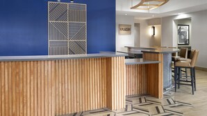 Un comptoir d’accueil avec un mur bleu et un panneau de séparation à motifs géométriques.