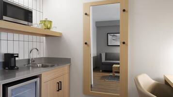 A modern kitchen with a built-in microwave, a coffee maker, and a refrigerator.