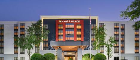A modern hotel with a prominent 'Hyatt Place' sign, featuring a symmetrical facade with large windows and a central entrance.