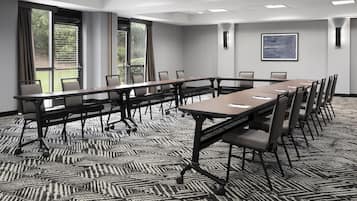 A conference room with a long table, chairs, and large windows.