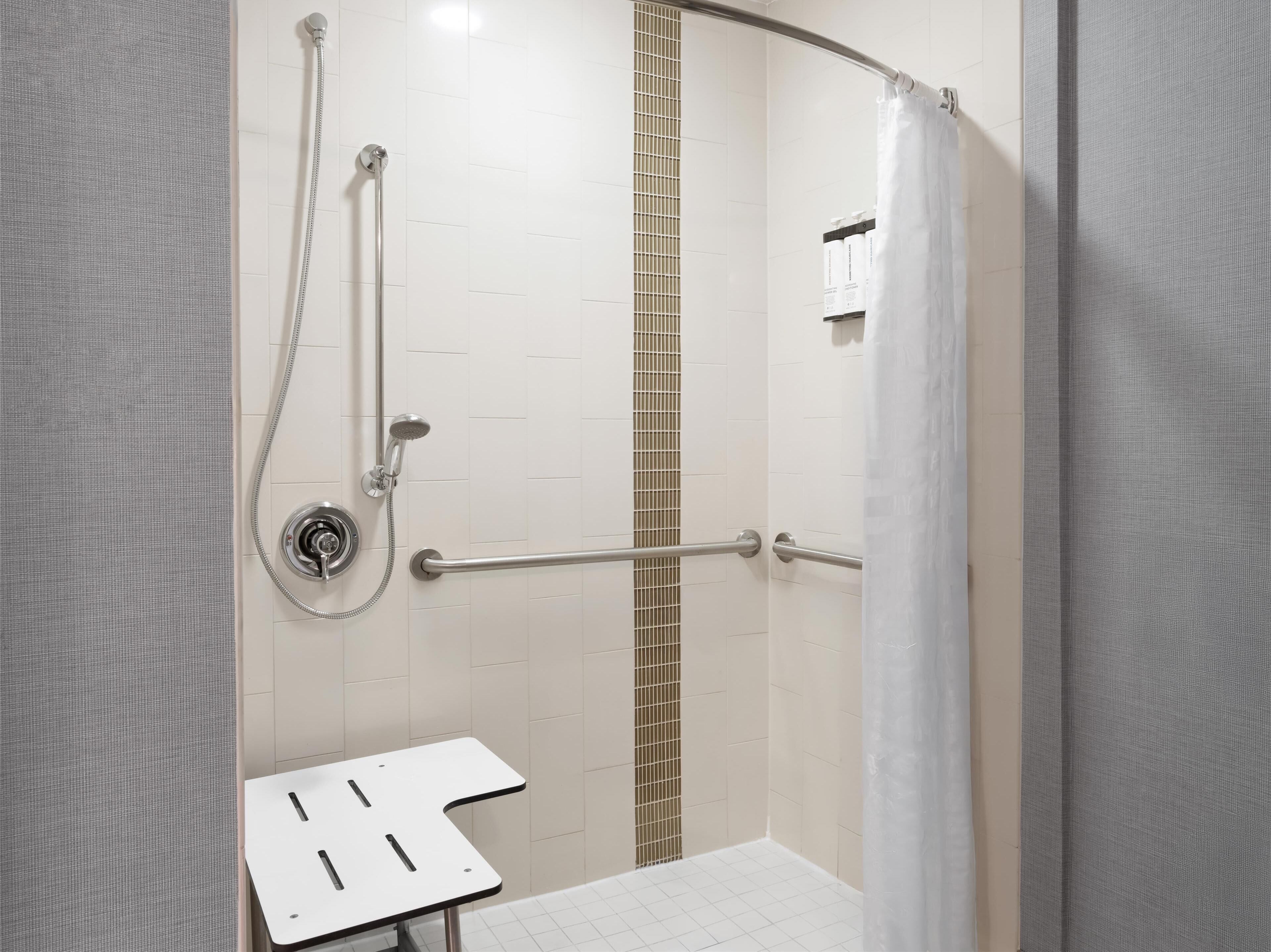 A shower with a handheld showerhead, a handheld shower attachment, and a handheld scrubber.