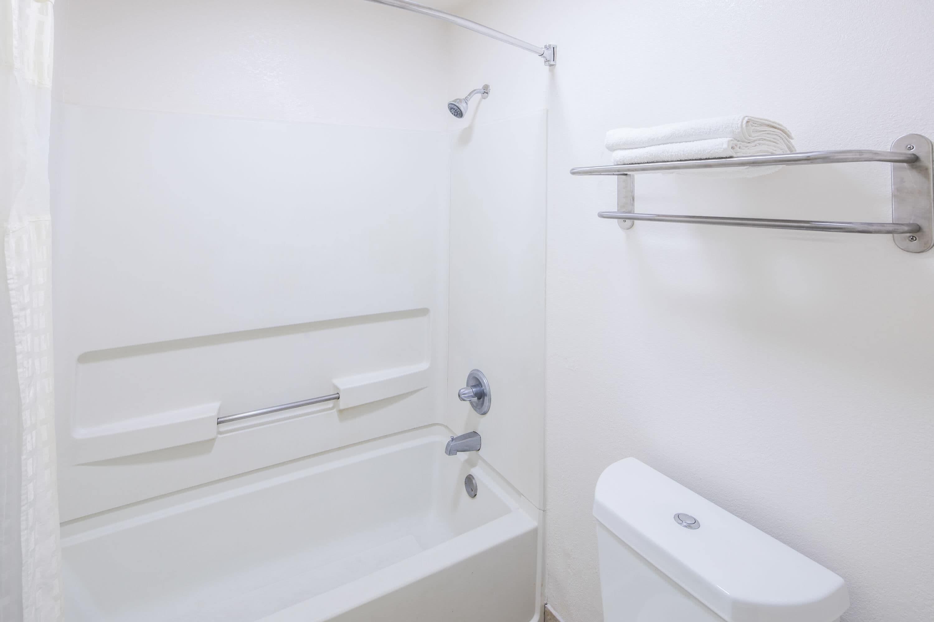 A bathroom with a bathtub, a toilet, a towel rack, and a showerhead.