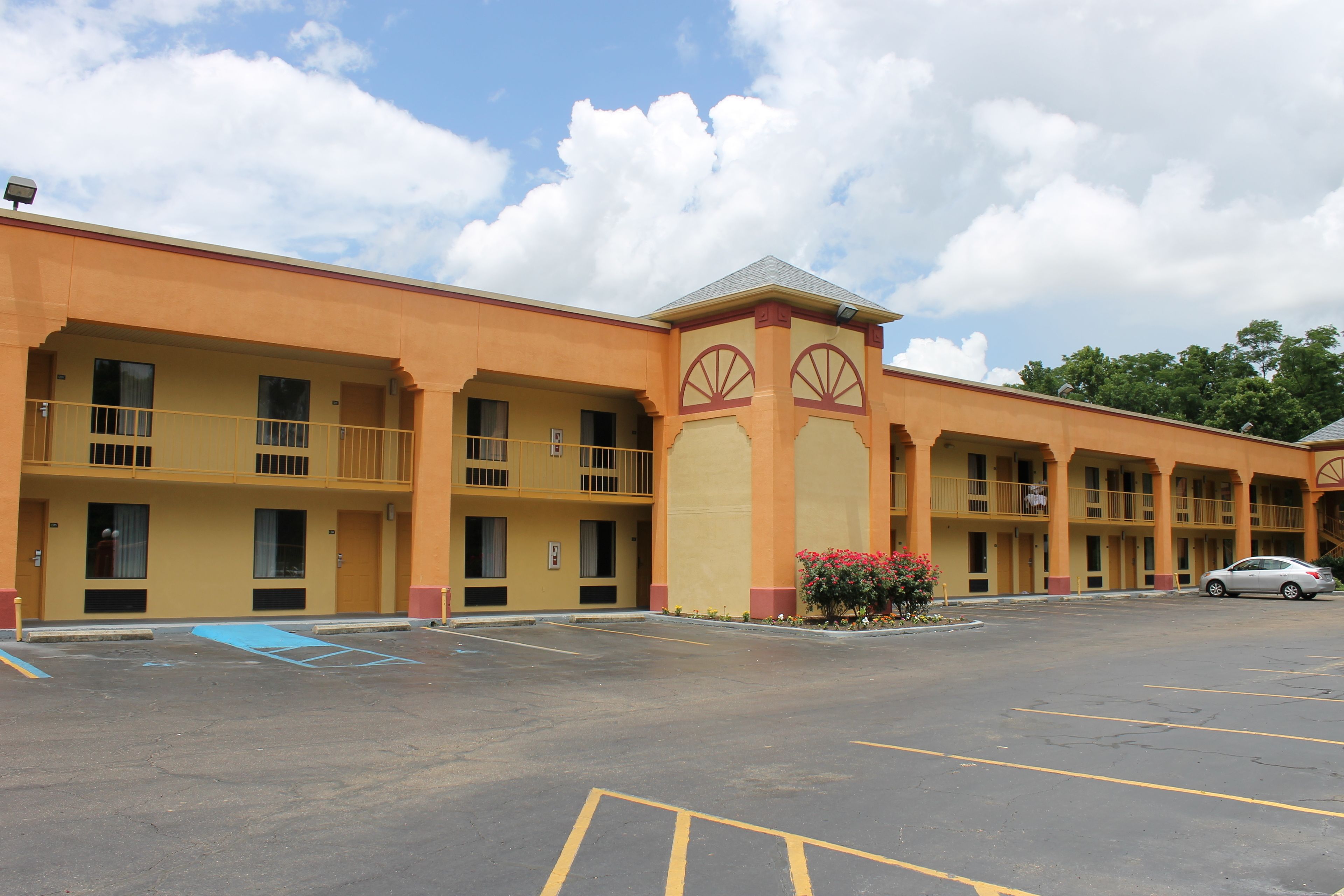 A multi-story motel with a yellow facade, balconies, and a parking lot.
